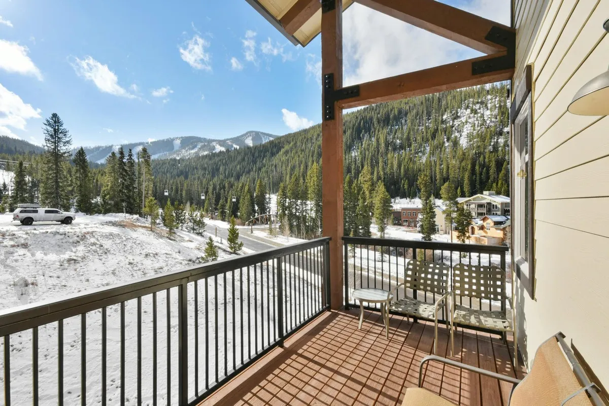 A peaceful balcony setup with comfortable seating overlooking snow-capped mountains and pine forests. The deck feels private and serene, ideal for unwinding with a hot beverage while enjoying the scenery.