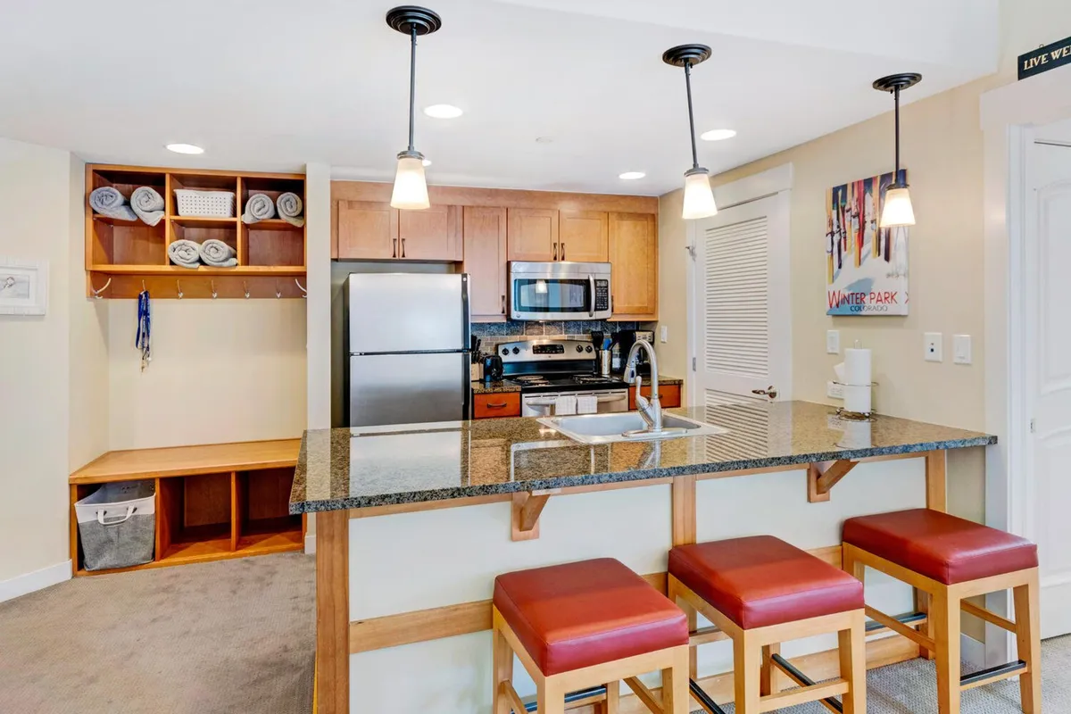 A spacious, modern kitchen featuring an inviting island with bar stools, open shelving, and gleaming stainless steel appliances. The setup encourages interaction, with ample space for meal preparation and casual conversation. The warm lighting and open layout foster a communal atmosphere perfect for group gatherings and culinary adventures.