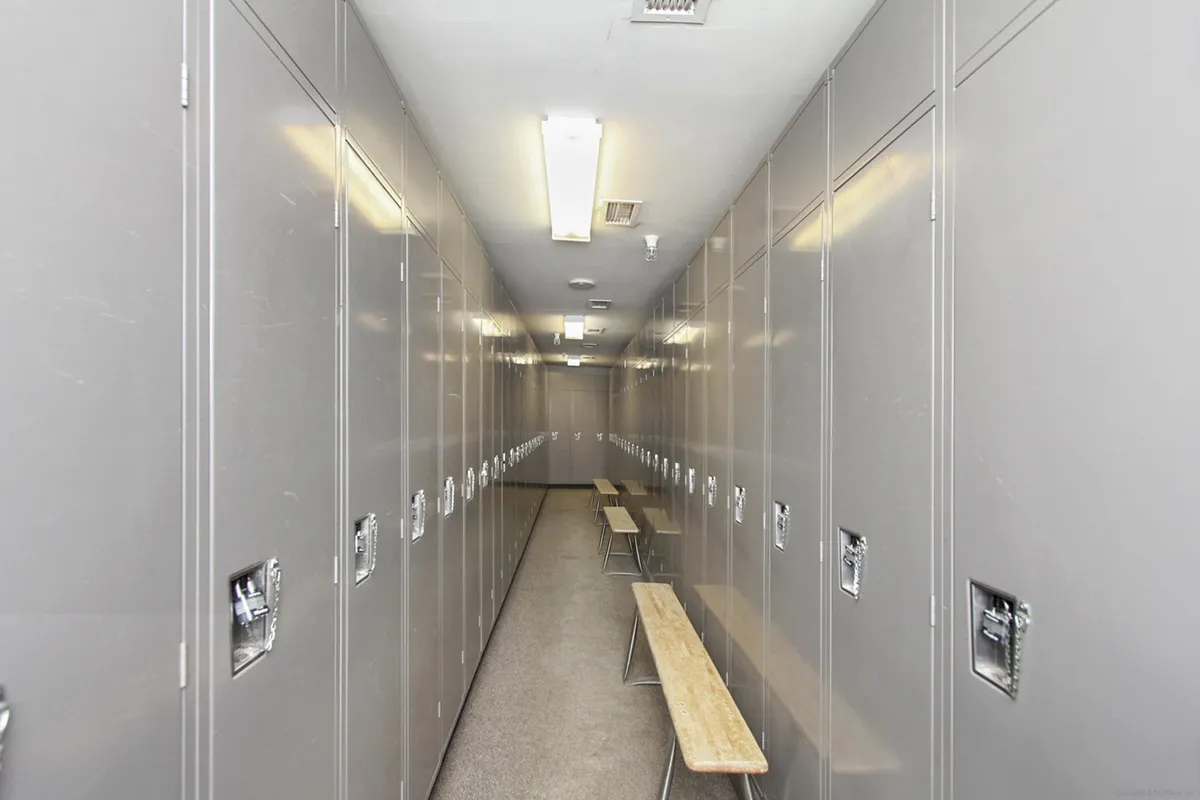 An interior view of secure metal lockers and benches under bright fluorescent lights. The utilitarian space is designed for guests to store gear, change clothes, and prepare for or wind down from outdoor activities, emphasizing convenience and safety for personal belongings.
